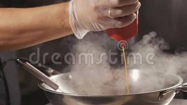厨师在炒菜锅里倒入酱汁的特写，慢动作。
